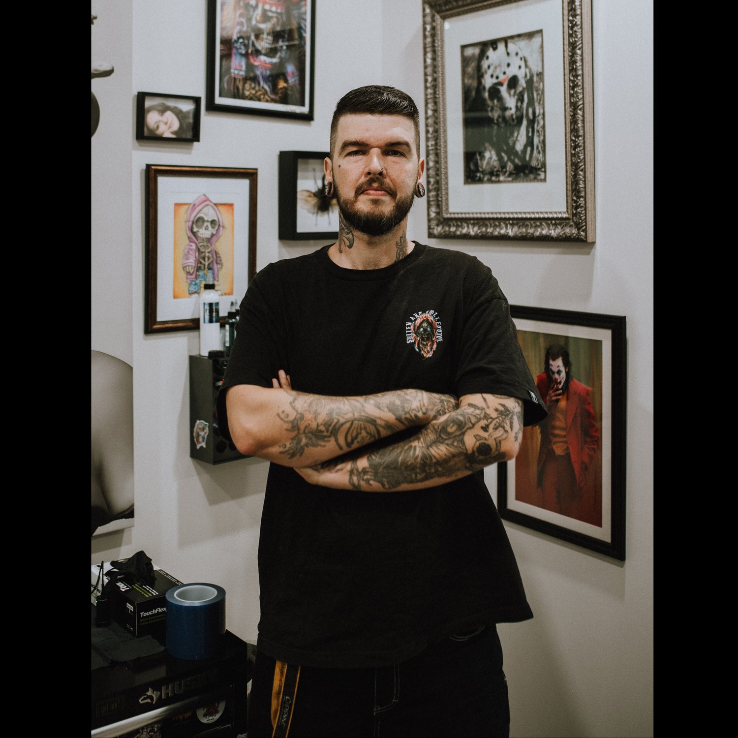 Tattoo artist Dominic at Sundog Studios in Airdrie standing in the studio with framed tattoo artwork