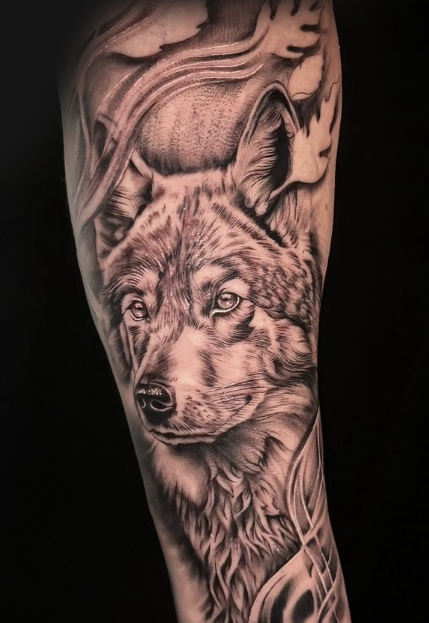 Black and grey realism wolf forearm tattoo with flowing ornamental background by Yvon_ink at Sundog Studios in Airdrie Alberta