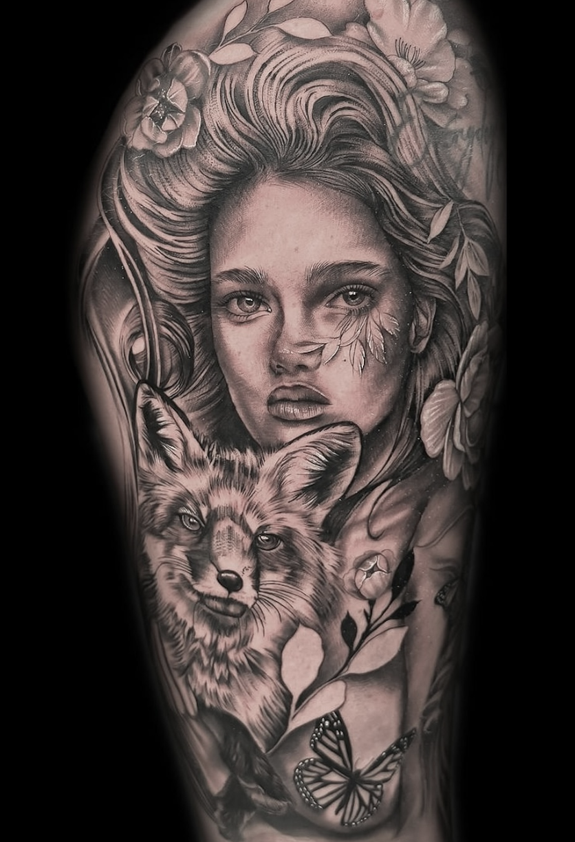 Black and white tattoo of a woman's face with a fox and floral elements by Yvon_ink at Sundog Studios in Airdrie Alberta.