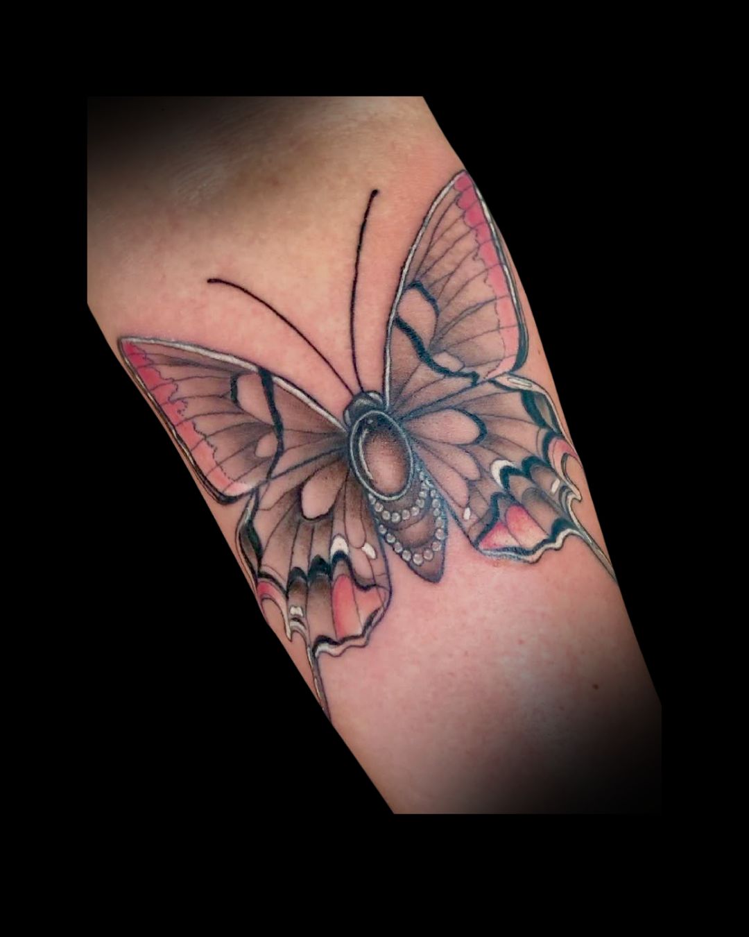 Butterfly tattoo with pink color and pearl details on a person's arm by Mahala, tattoo artist at Sundog Studios in Airdrie Alberta