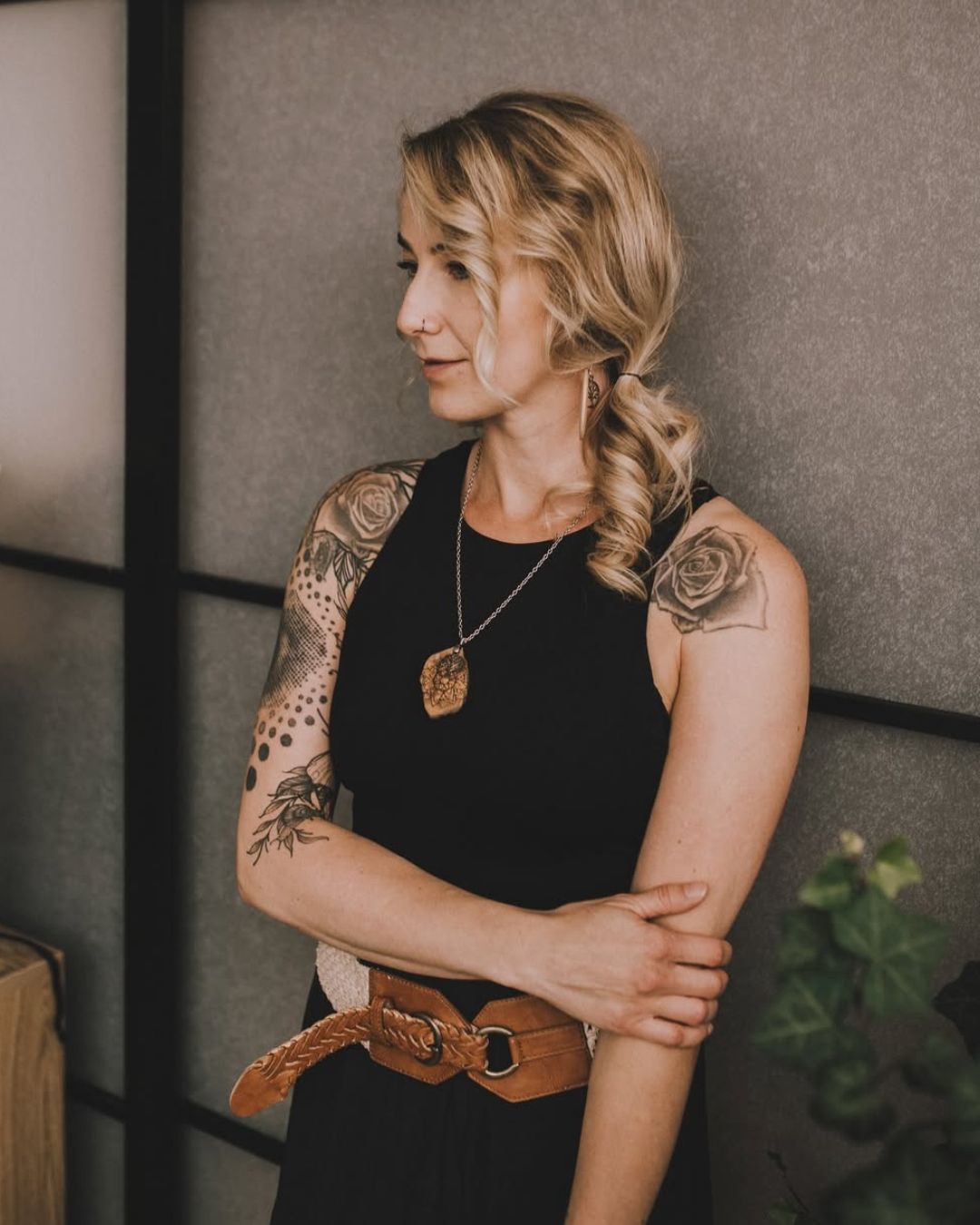 Channy a tattoo artist at Sundog Studios in Airdrie Alberta standing in front of a glass door with tattoo sleeves