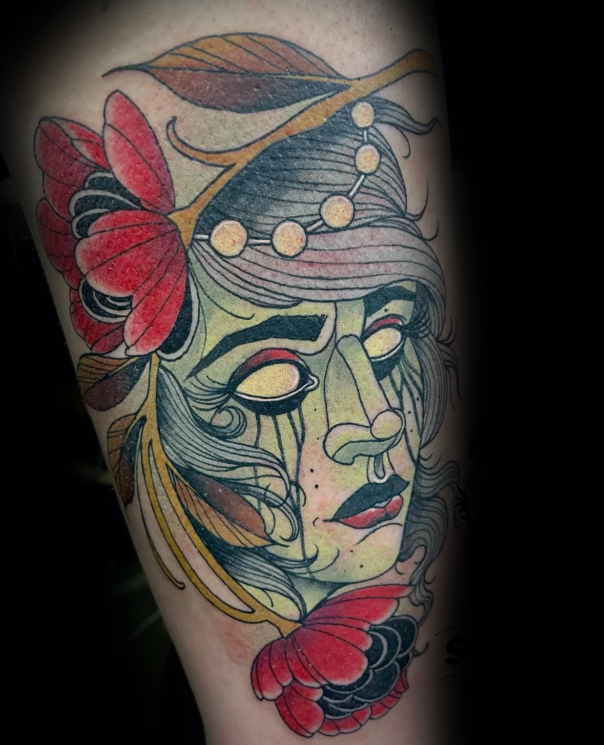 Colour tattoo of a woman's face with red flowers and leaves by Rob Adams, tattoo artist at Sundog Studios in Airdrie Alberta