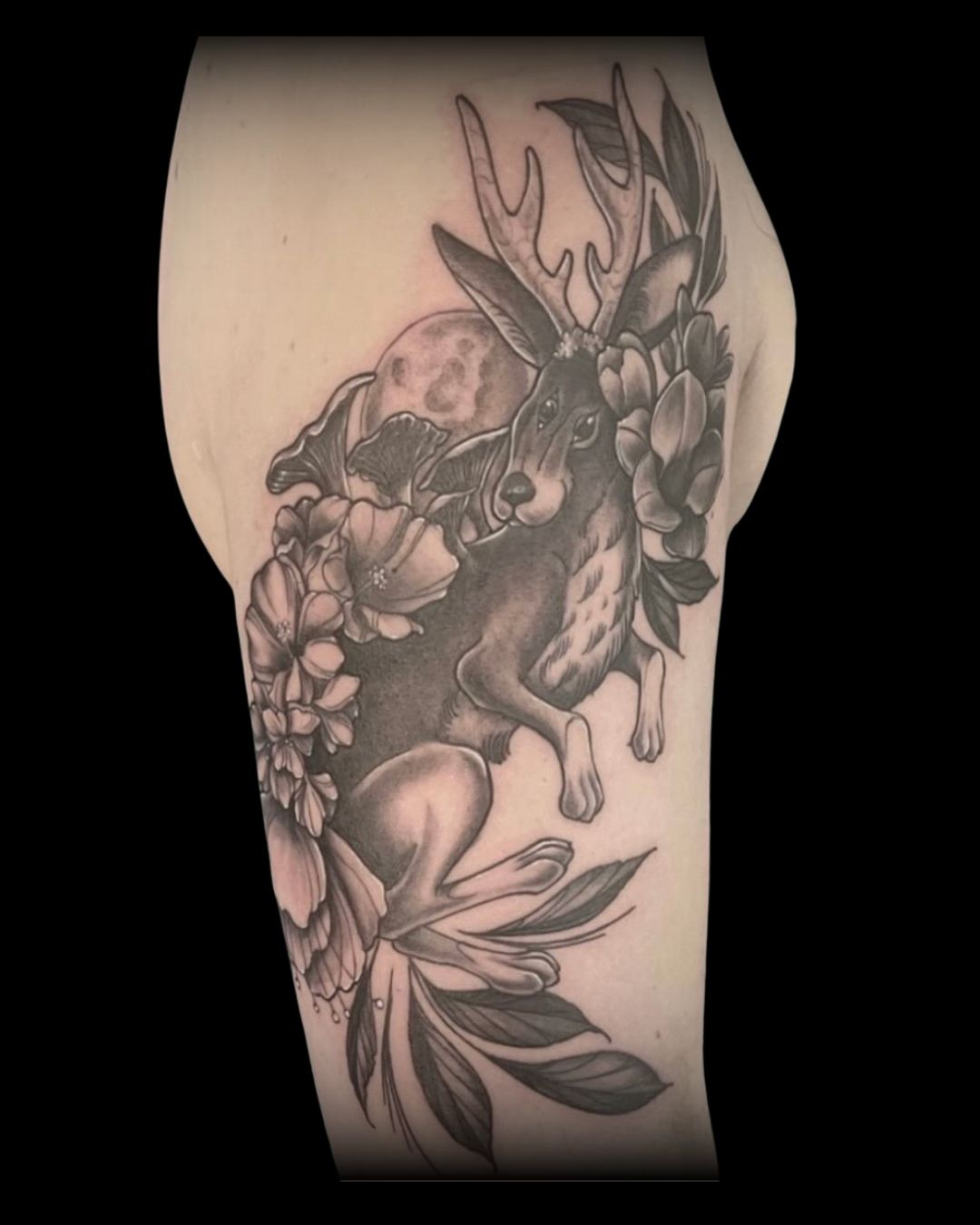 Black and gray tattoo of a deer with floral elements on a person's arm by Channy, tattoo artist at Sundog Studios in Airdrie Alberta