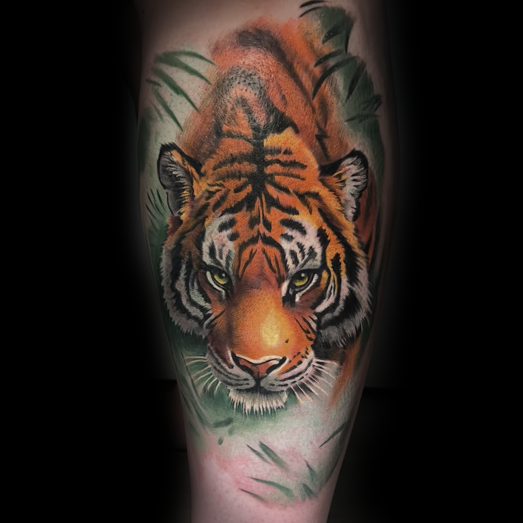 colored Tattoo of a tiger's face with green leaves credit to Dominic