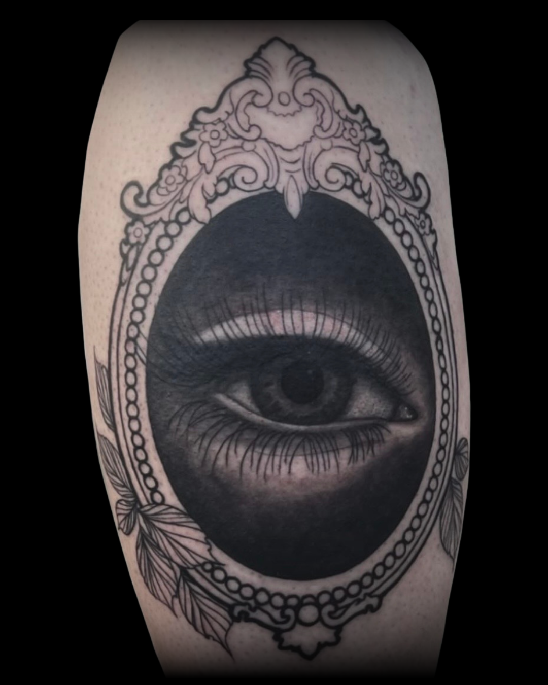 Tattoo of an eye with long lashes on a decorative frame by Channy tattoo artist at Sundog Studios in Airdrie Alberta