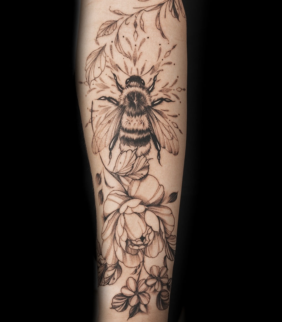 Fine line bee and floral forearm tattoo by Sundog Studios tattoo artists in Airdrie Alberta