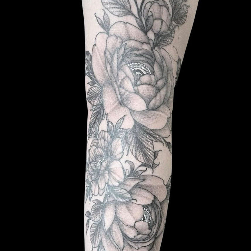 Floral tattoo fine line design on a leg by Mahala, tattoo artist at Sundog Studios in Airdrie Alberta