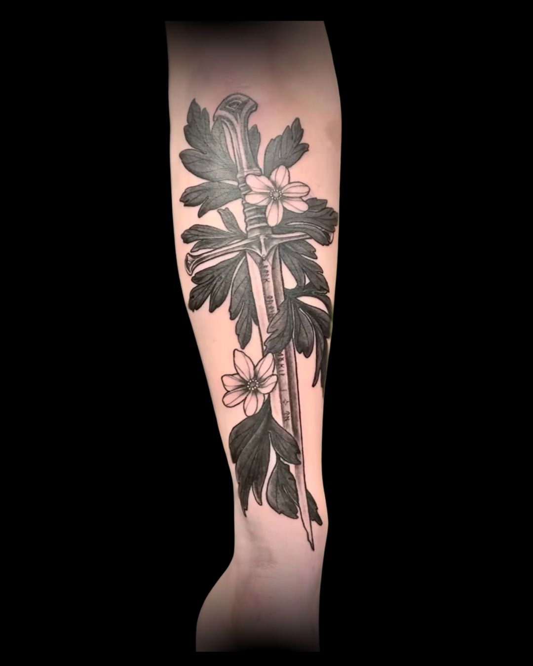 Tattoo of a floral design with a sword on a person's arm by Channy, tattoo artist at Sundog Studios at Airdrie Alberta