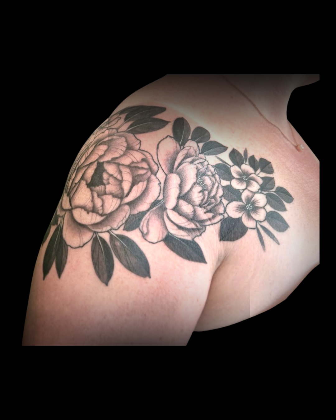 Floral tattoo on a person's shoulder with black and grey colors by Channy, tattoo artist at Sundog Studios in Airdrie Alberta