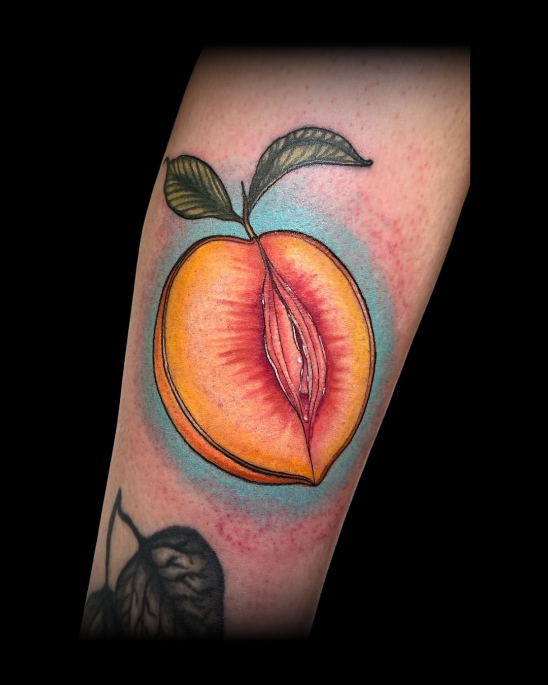 Colorful tattoo of a half peach surrounded with leaves on a person's arm by Mahala, tattoo artist at Sundog Studios in Airdrie Alberta