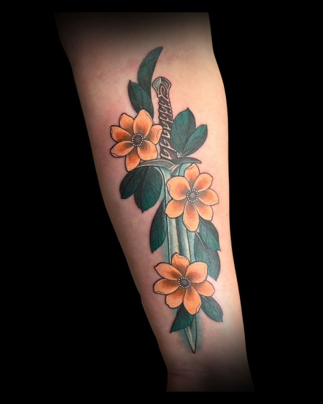 Tattoo of orange flowers with green leaves and a sword on a person's arm by Channy, tattoo artist at Sundog Studios in Airdrie Alberta